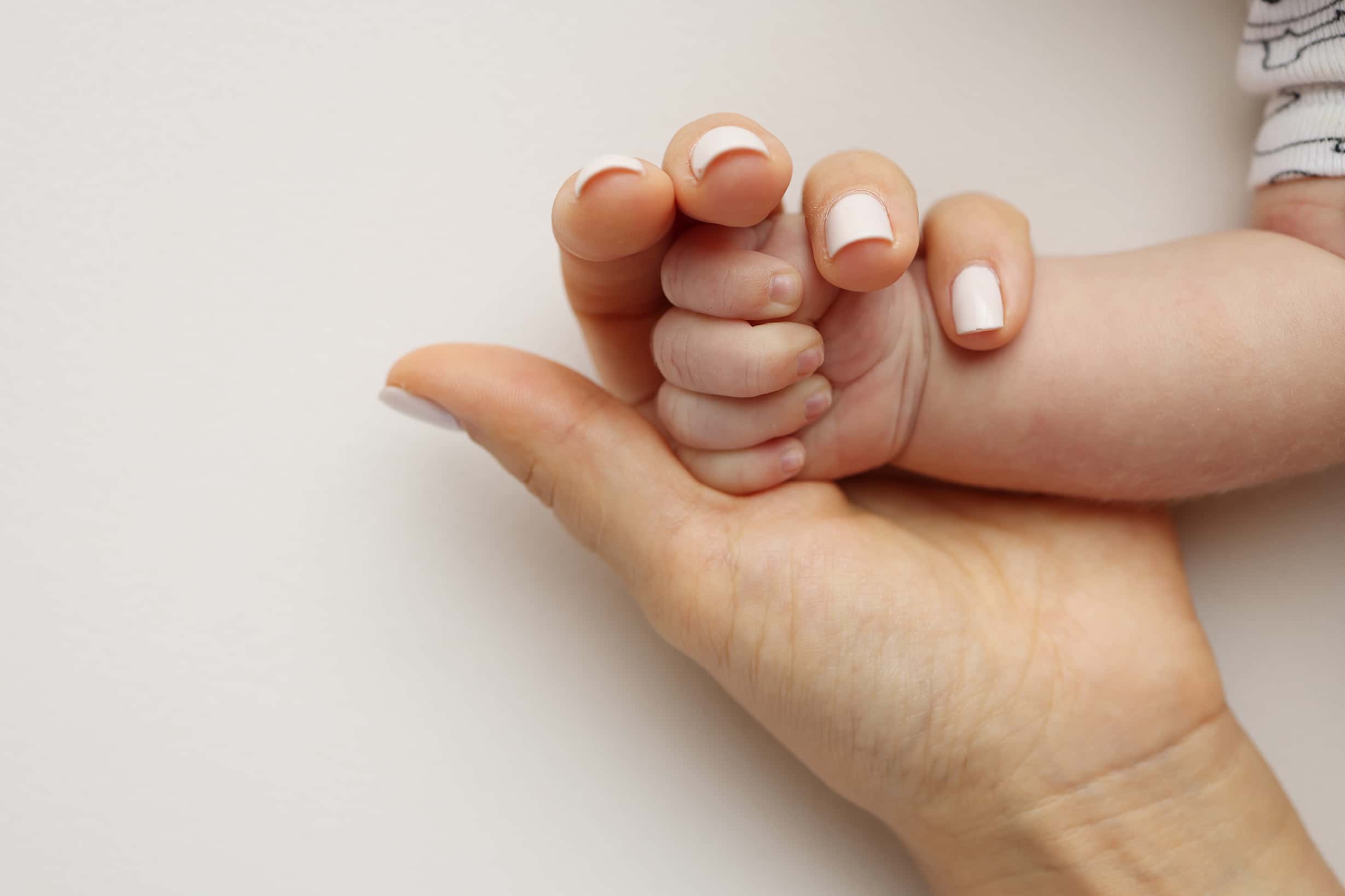 Hands hold the fingers of a newborn baby. The hand of mother.