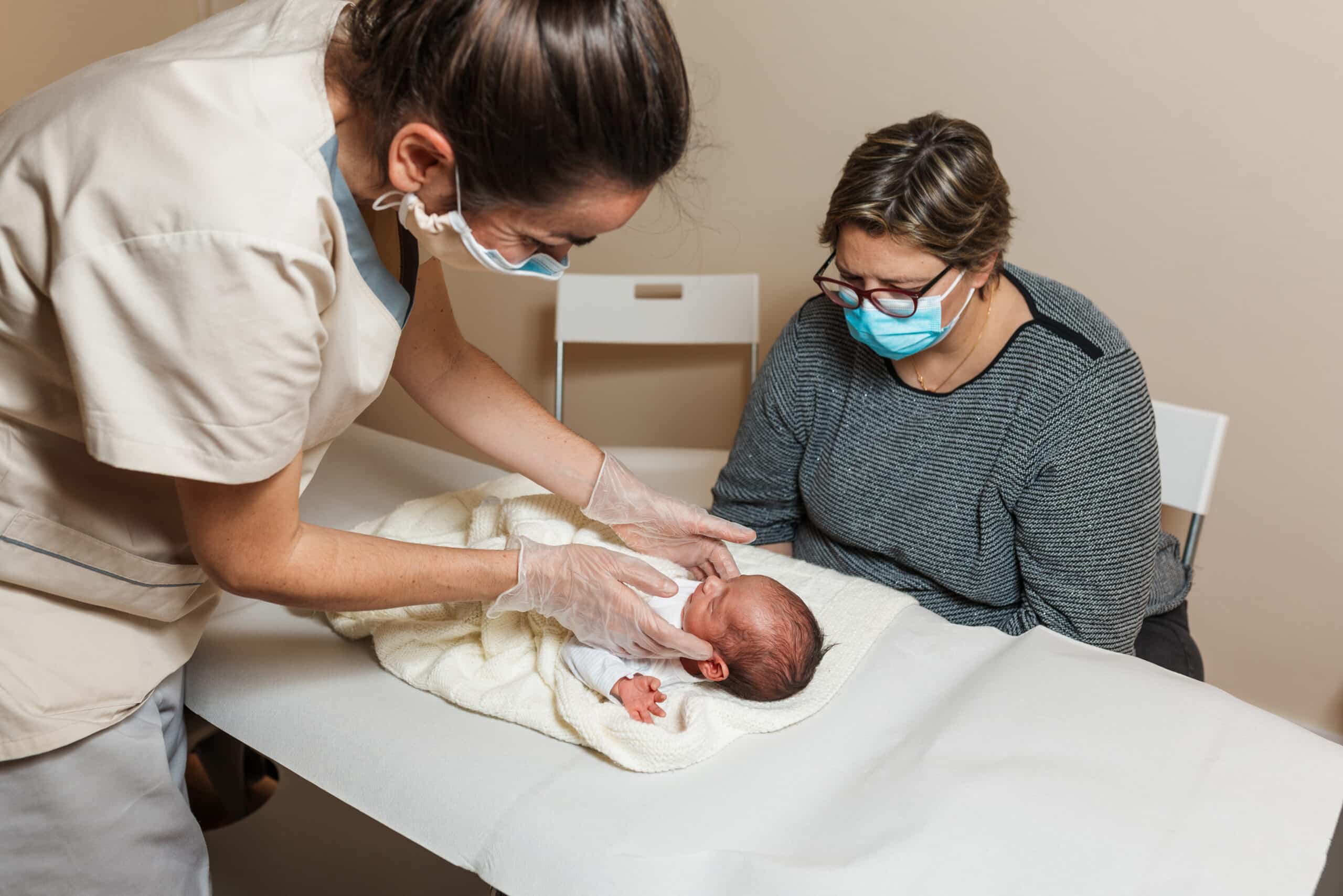 Midwife doing an evaluation of the temporomandibular joints on a baby at a medical center.